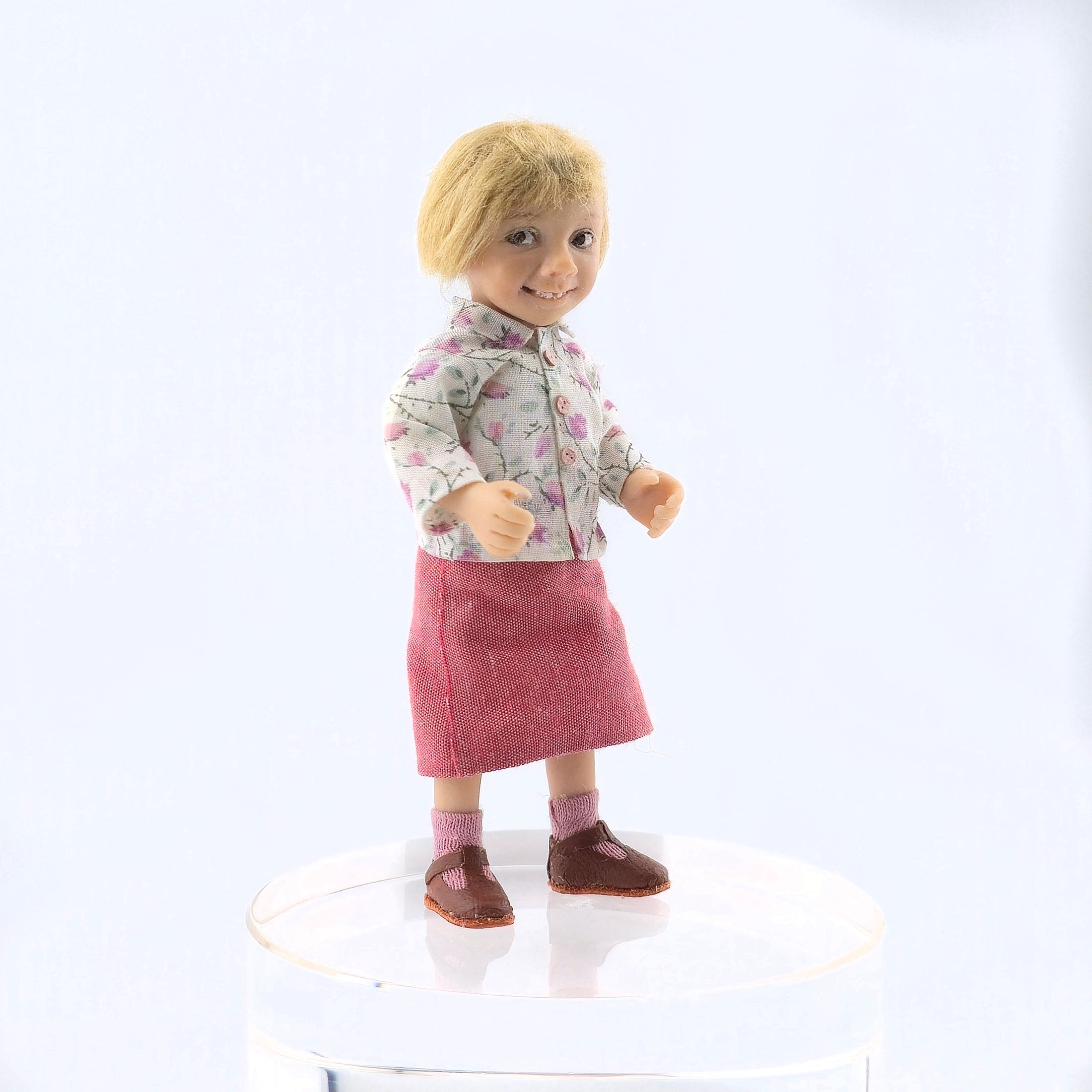 Catherine Muniere Doll with blonde hair wearing a floral shirt and pink skirt on a white background