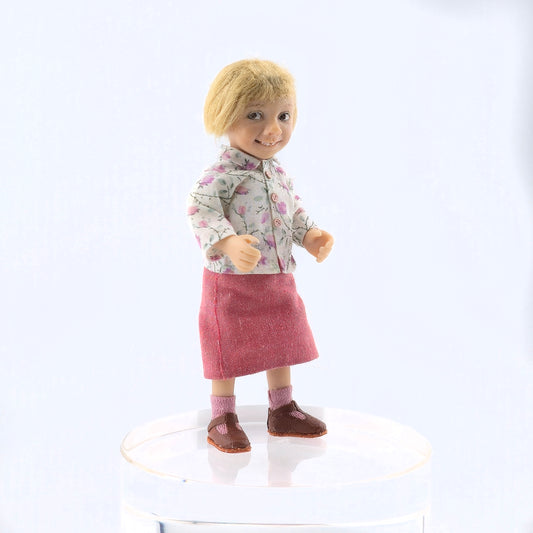 Catherine Muniere Doll with blonde hair wearing a floral shirt and pink skirt on a white background