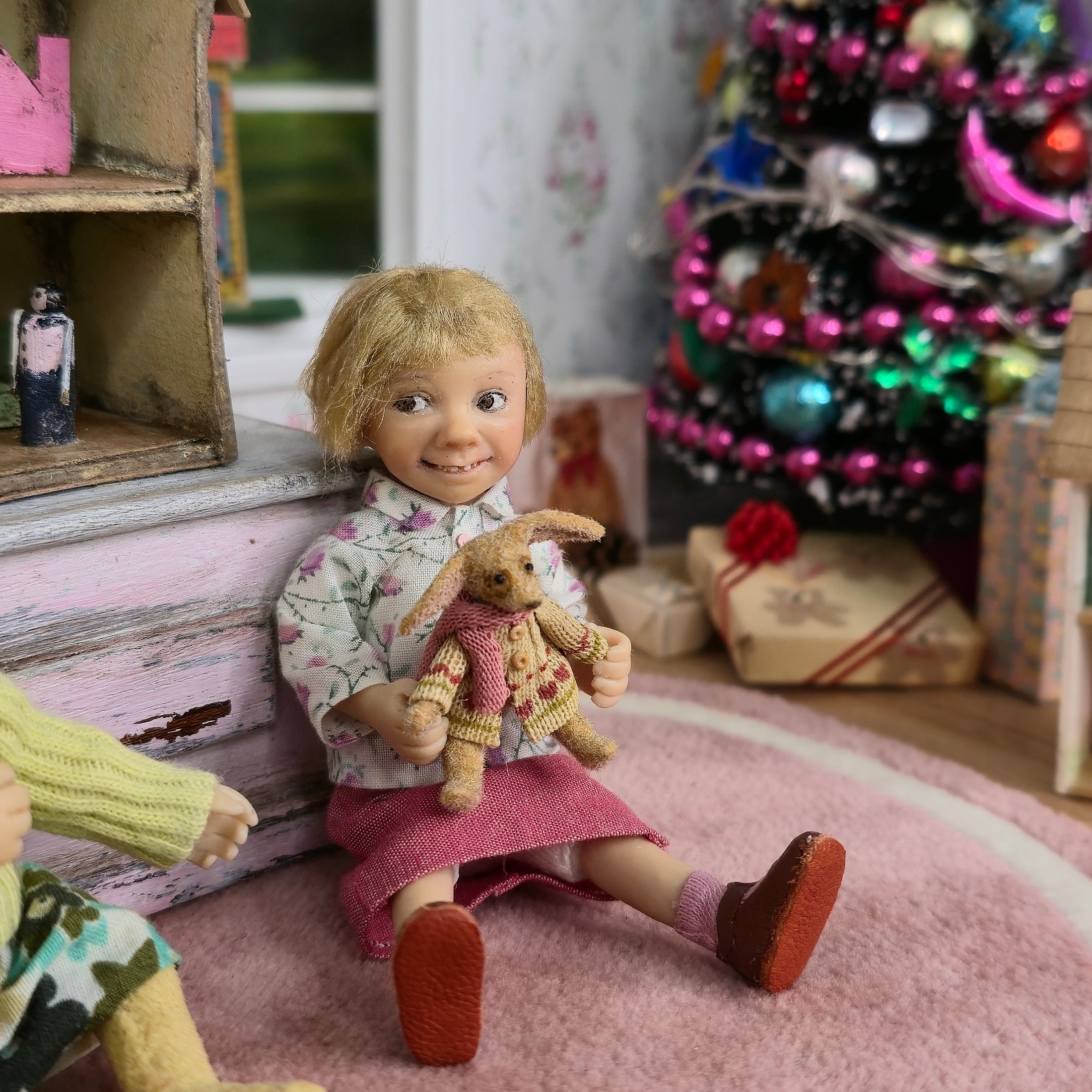 Catherine Muniere Doll with blonde hair and a floral top seated in a playroom