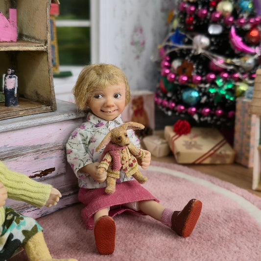 Catherine Muniere Doll with blonde hair and a floral top seated in a playroom
