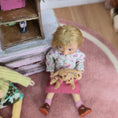 Load image into Gallery viewer, Catherine Muniere Doll holding a toy in a playroom.
