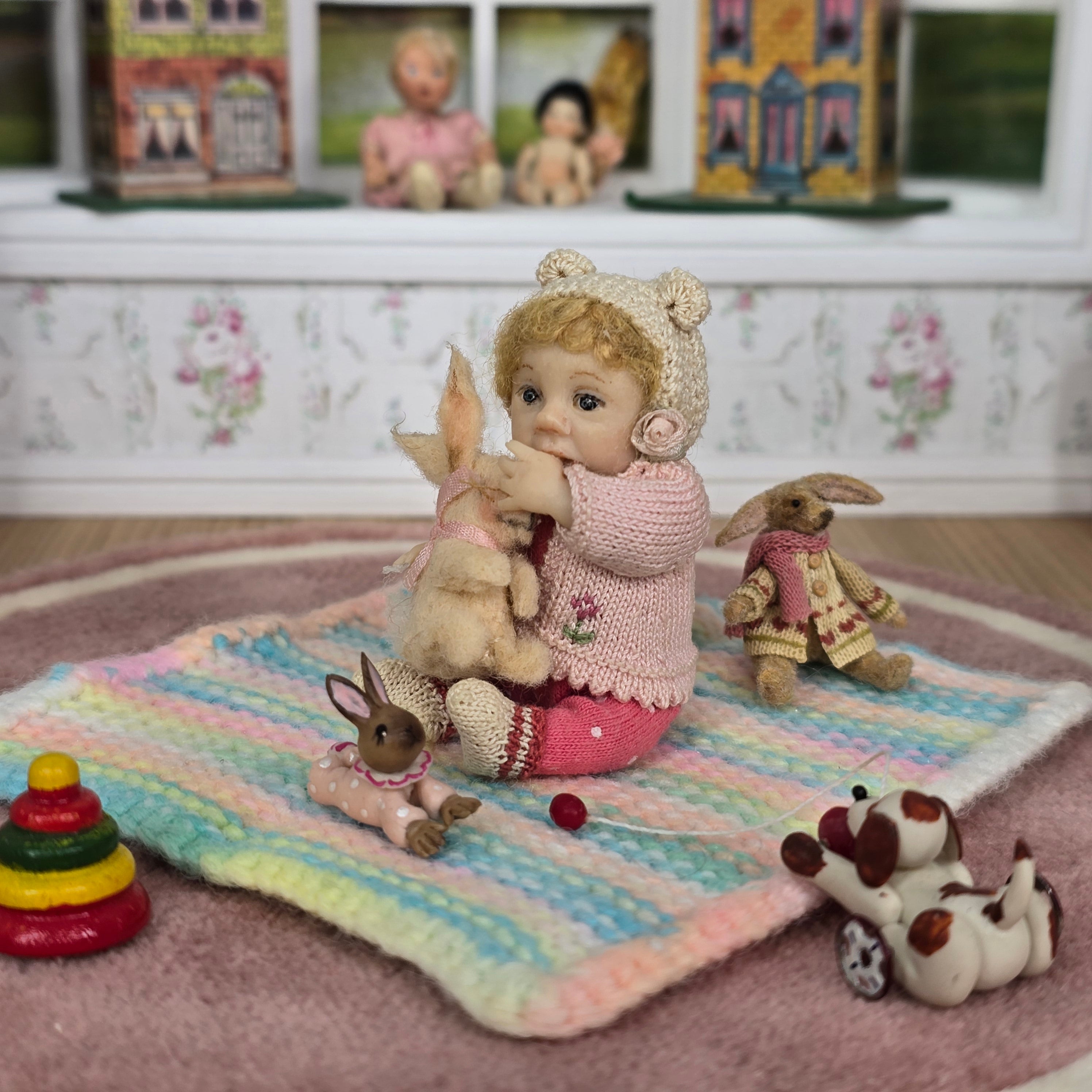Catherine Muniere doll with rabbit toys on a colorful blanket in a room with vintage decor