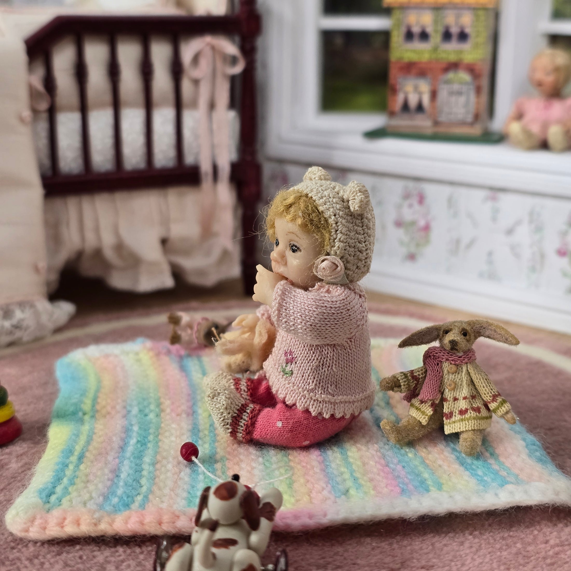 Catherine Muniere doll and rabbit on a colorful striped blanket in a cozy room.