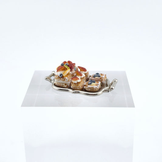 miniature pastries on a silver tray with a white background