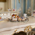 Load image into Gallery viewer, Delicate miniature pastries on a silver tray with a decorative table setting in the background
