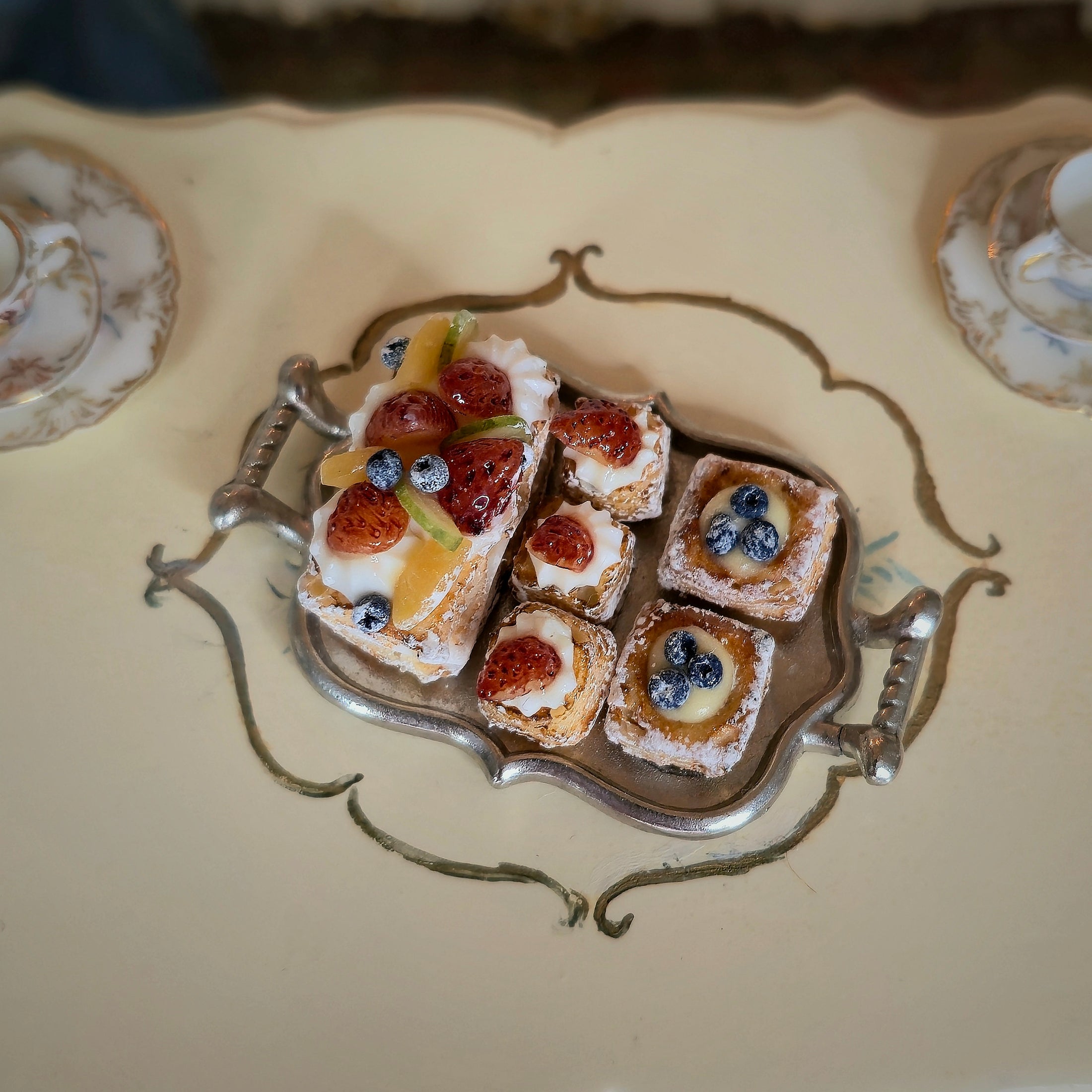Decorative silver tray with small pastries on a decorative plate