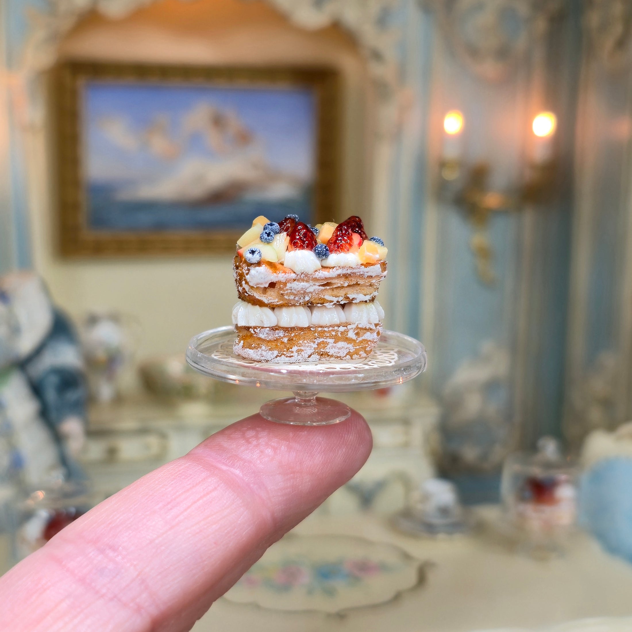 Miniature dessert on a clear stand held by a finger with a decorative background