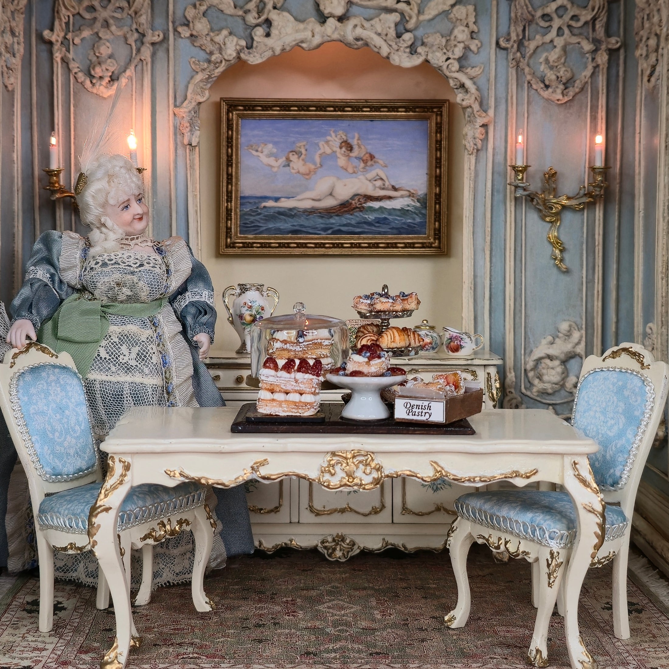 Decorative interior with a doll, table set with pastries, and ornate wall decorations.