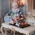 Load image into Gallery viewer, Miniature doll with a table of pastries in a decorative setting
