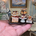 Load image into Gallery viewer, Miniature Danish pastries on a tray held in a hand with a decorative background.
