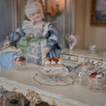 Load image into Gallery viewer, Miniature doll in a decorative setting with a cake and tea set.
