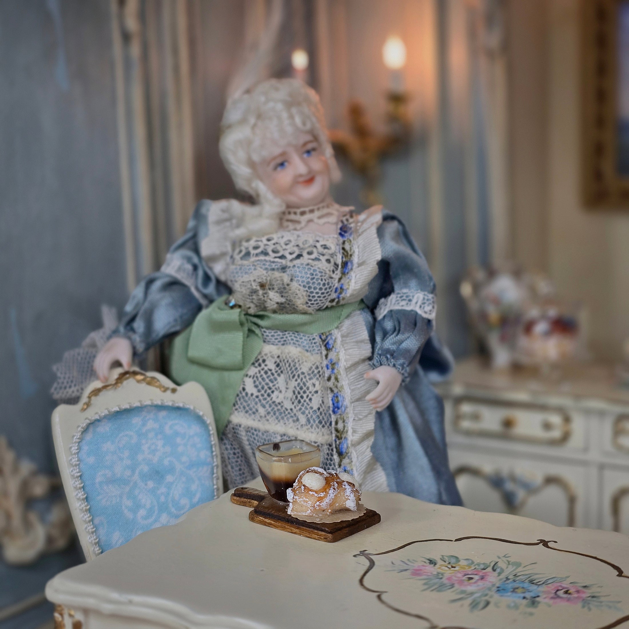Vintage-style doll in a decorative setting with a table and chair.