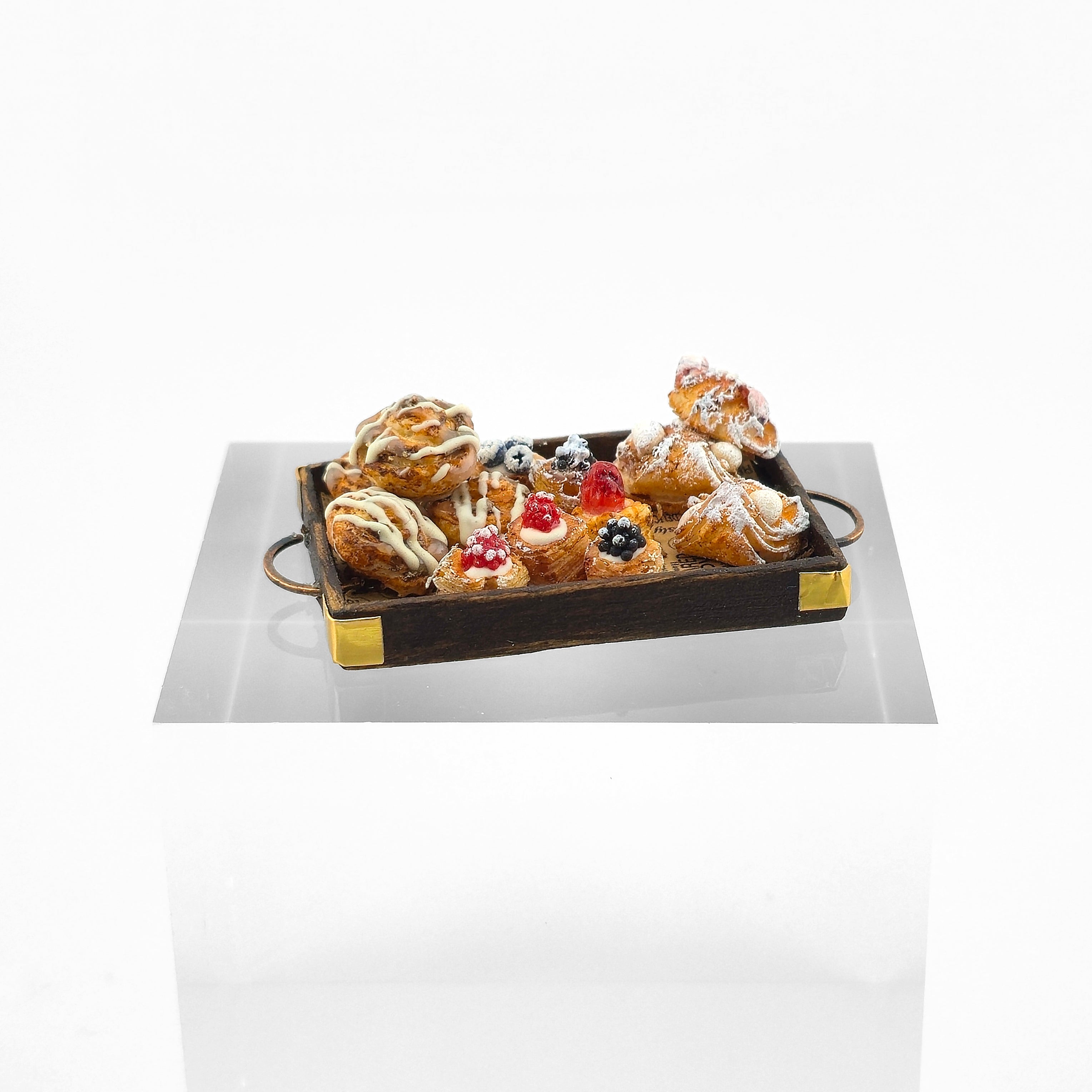 Assorted pastries on a decorative tray with a white background