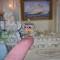 Load image into Gallery viewer, Miniature pastry under a clear dome held by a finger, with a dollhouse setting in the background.

