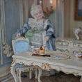 Load image into Gallery viewer, Miniature tea cup and cupcake diorama on a decorative table with a doll in the background
