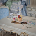 Load image into Gallery viewer, A cup of tea and a small cupcake on a decorative table.
