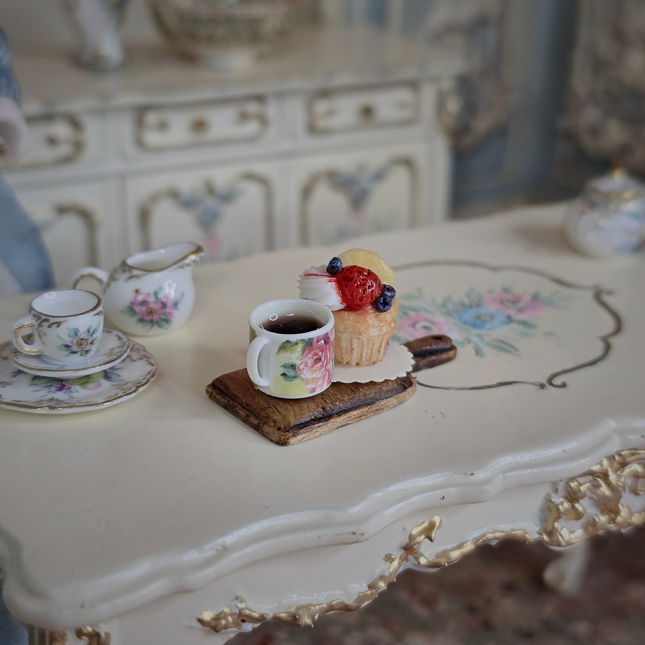 Tea cup and cupcake on a decorative table.