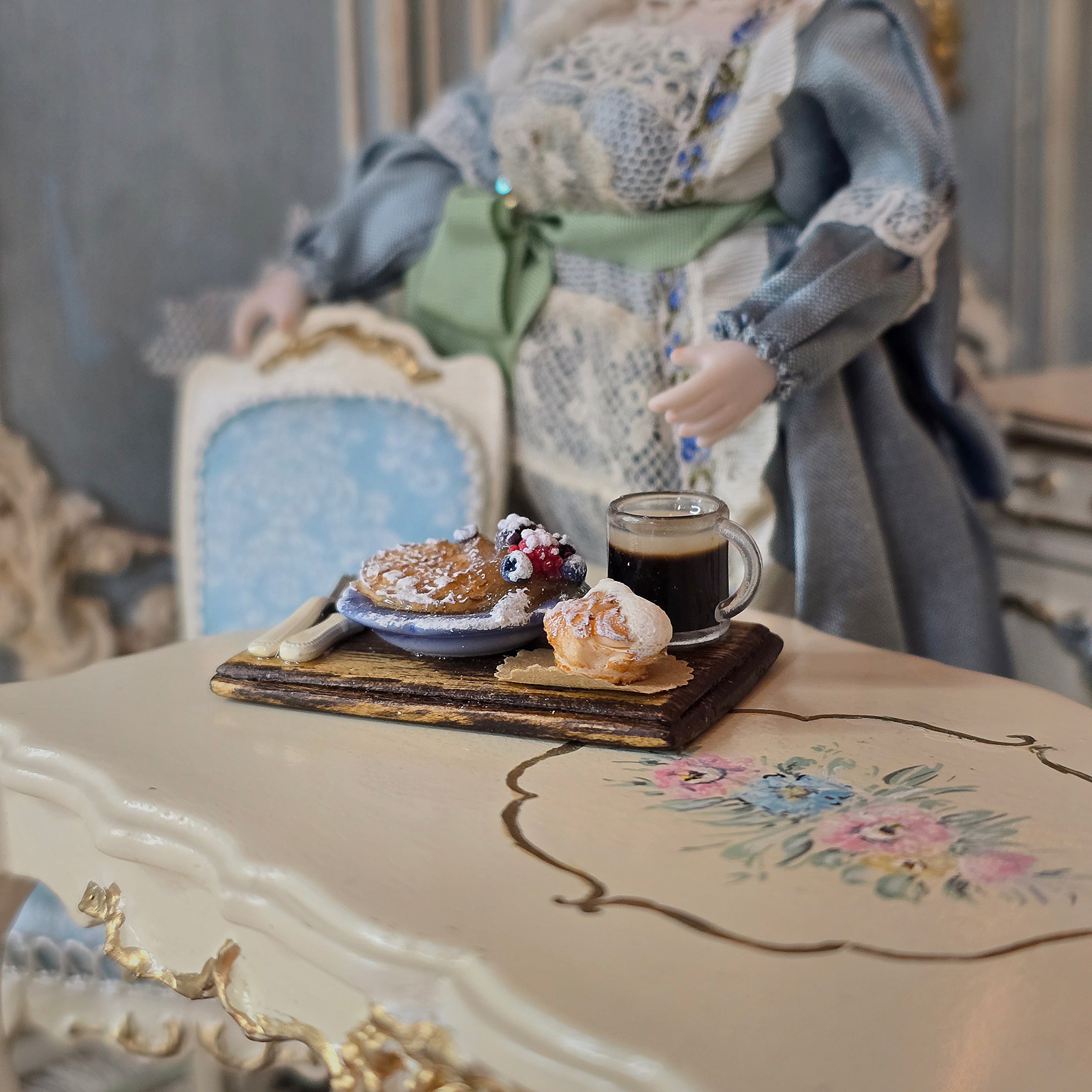 Miniature table setting with food and a doll in a decorative room.