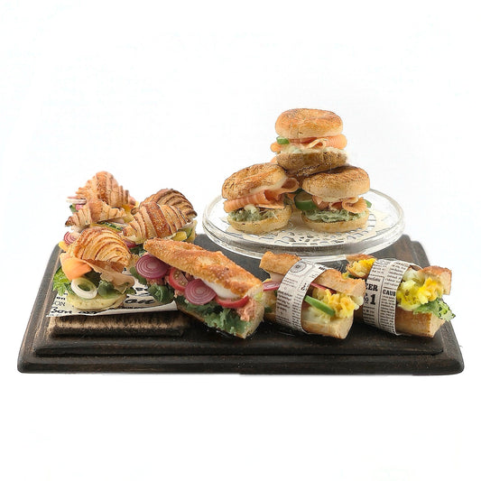 Assorted sandwiches on a wooden tray with a white background