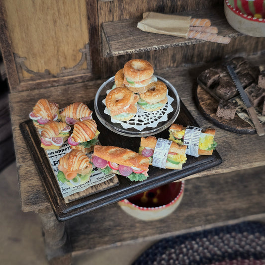 Miniature food display with sandwiches and bagels.