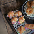 Load image into Gallery viewer, Small sandwiches on a tray with a newspaper underneath, on a wooden surface.
