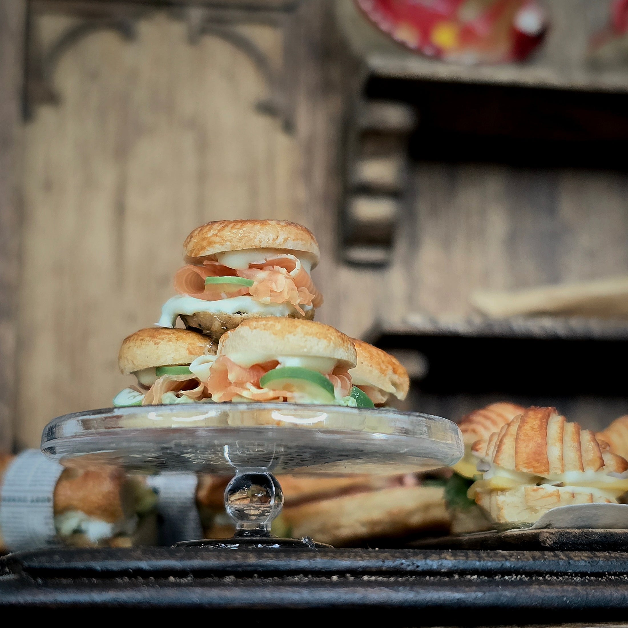 Stack of sandwiches on a clear cake stand with a rustic background