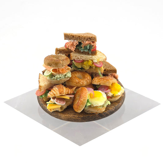 Tower of assorted sandwiches on a wooden board with a white background