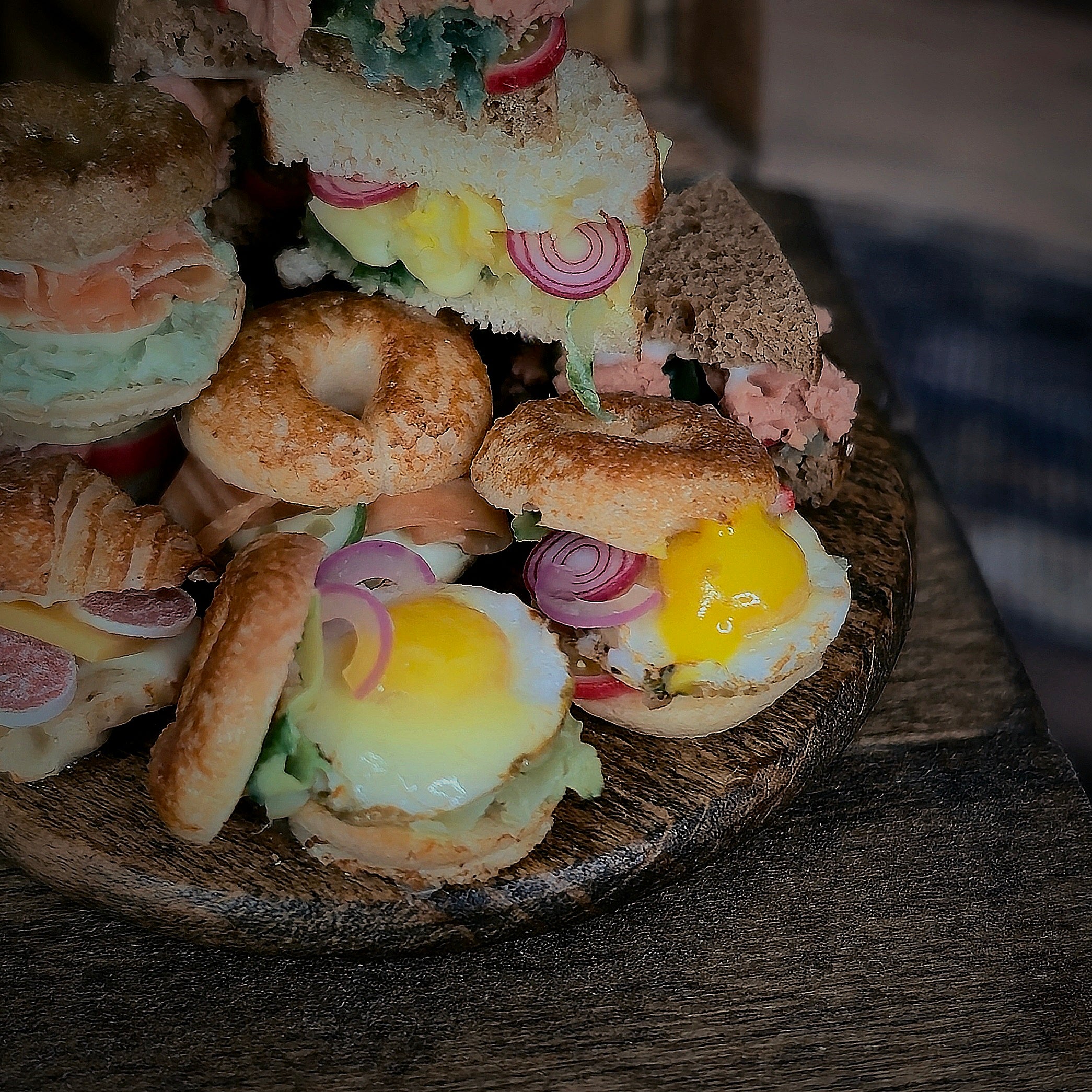 Assorted sandwiches with eggs and vegetables on a wooden plate