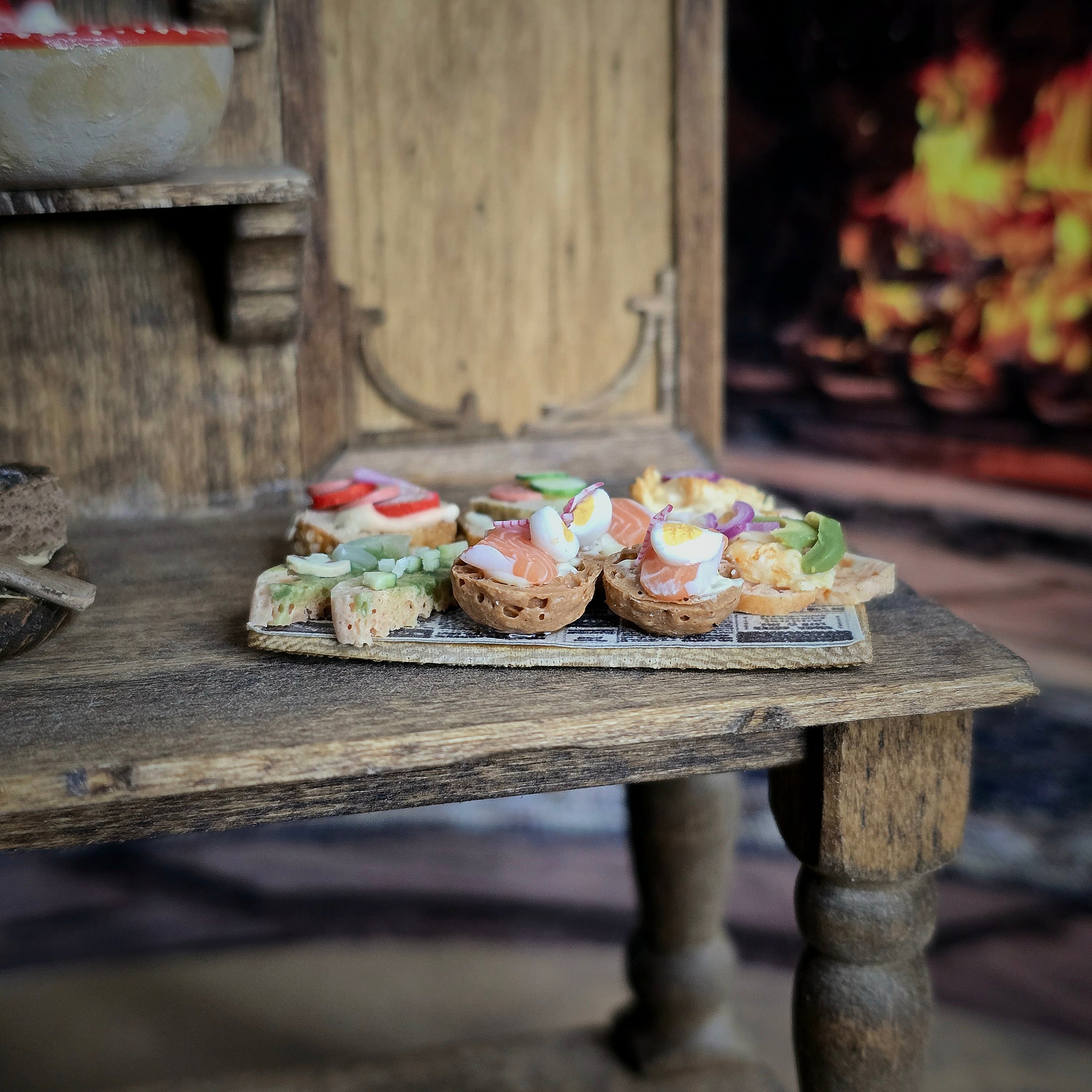 Small food platter with sandwiches on a rustic wooden table in front of a fireplace.