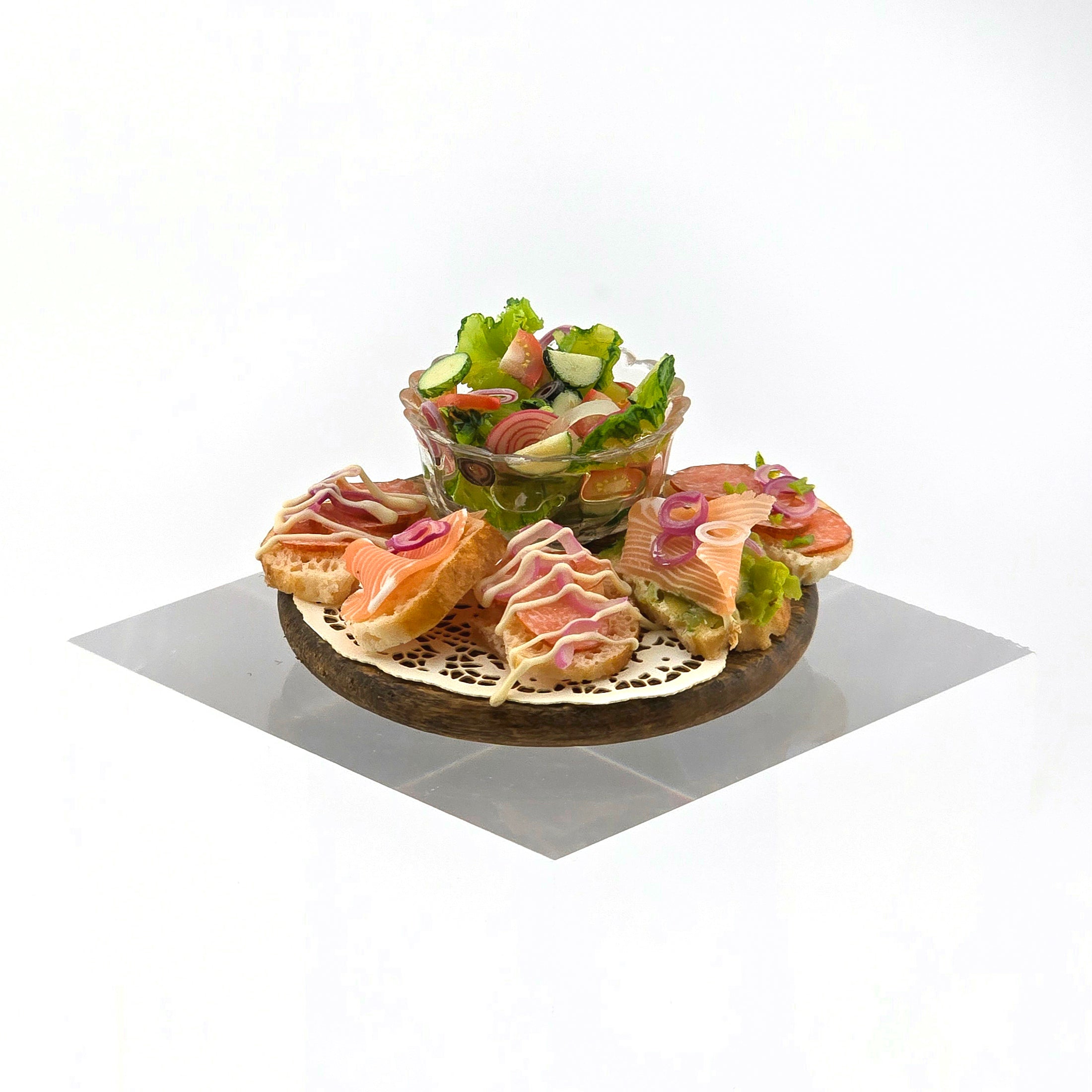 Platter of sandwiches and a bowl of salad on a white background