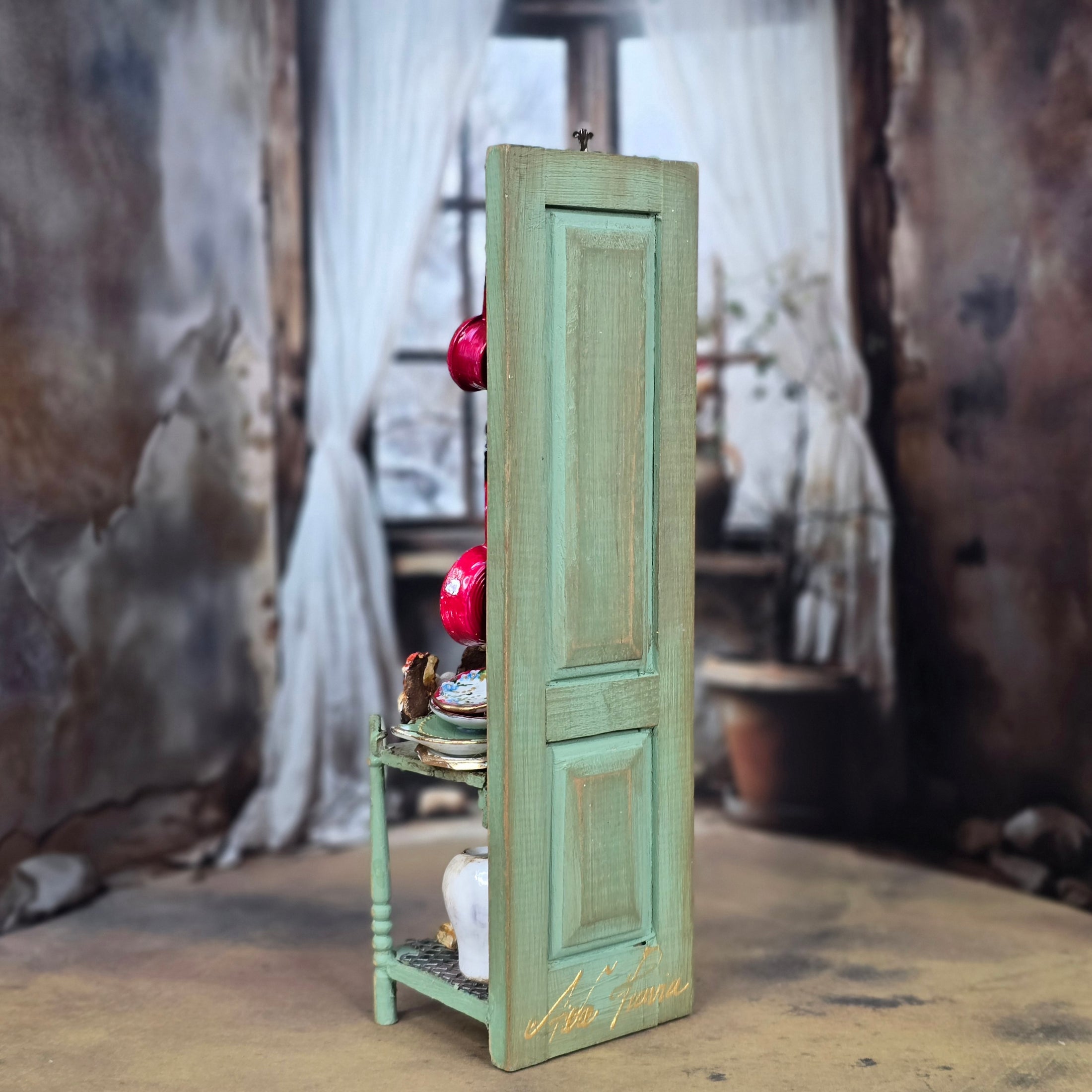 Small green door with decorative items on a textured surface
