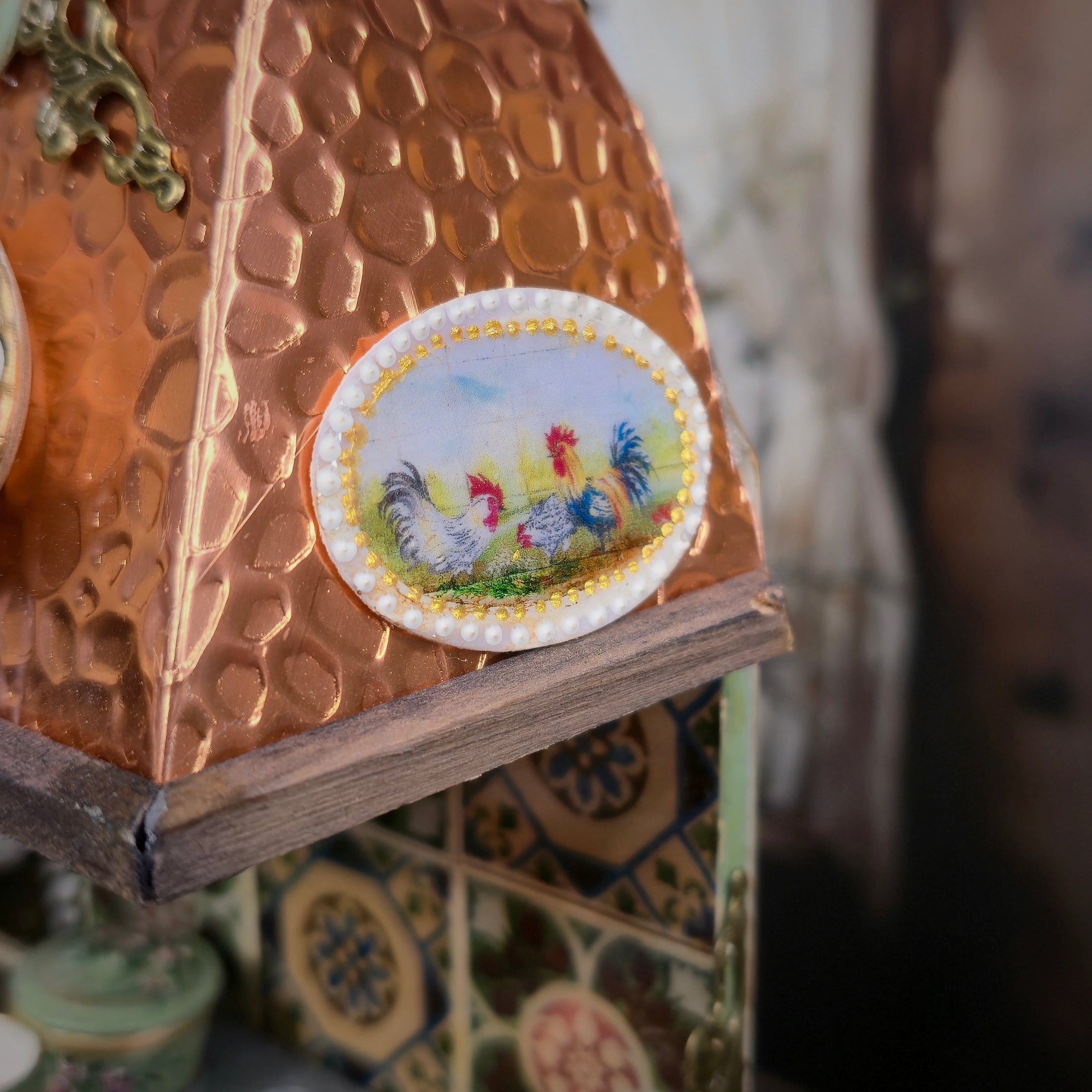 Decorative copper stove topper with a painted plaque featuring roosters.