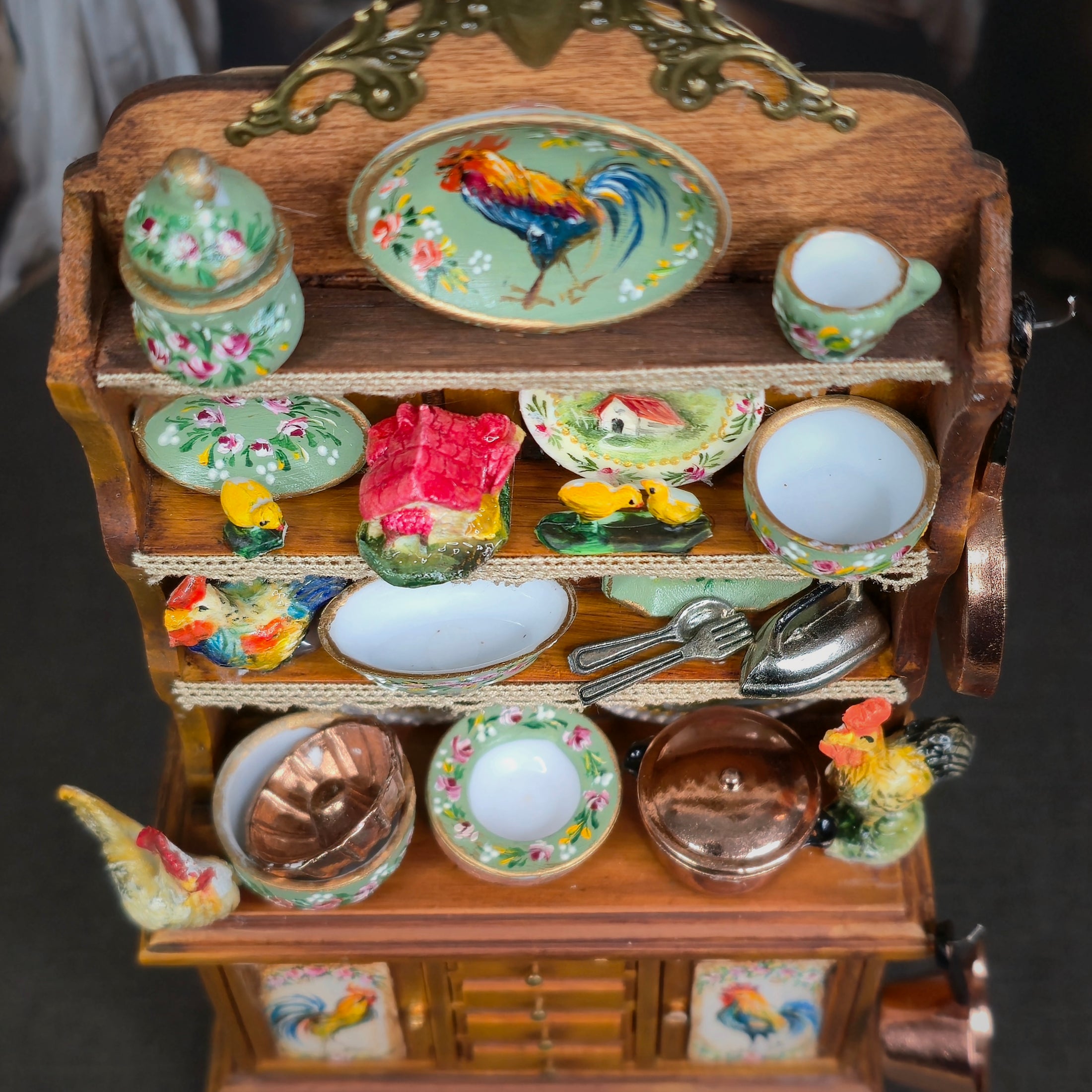 Miniature wooden kitchen set with ceramic items and rooster design on a dark background