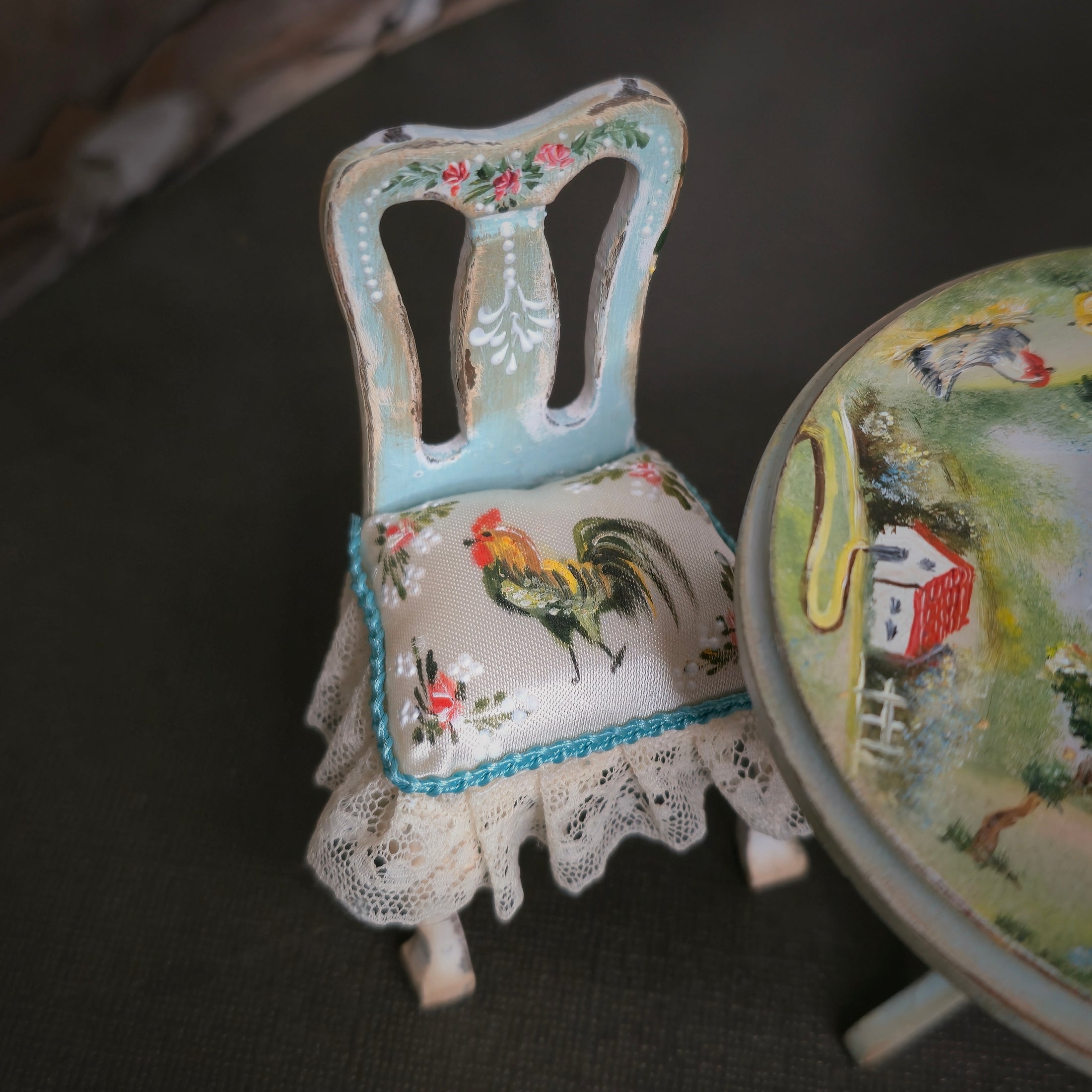 Decorative miniature chair with rooster design on a dark surface