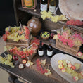 Load image into Gallery viewer, Decorative setup with fruits, bottles, and wooden crates on a table.
