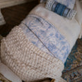 Load image into Gallery viewer, Close-up of a woven blanket with a blue and white toile fabric on top.
