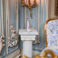 Load image into Gallery viewer, Decorative interior with ornate wall paneling, a small statue on a pedestal, and a chair with patterned fabric.

