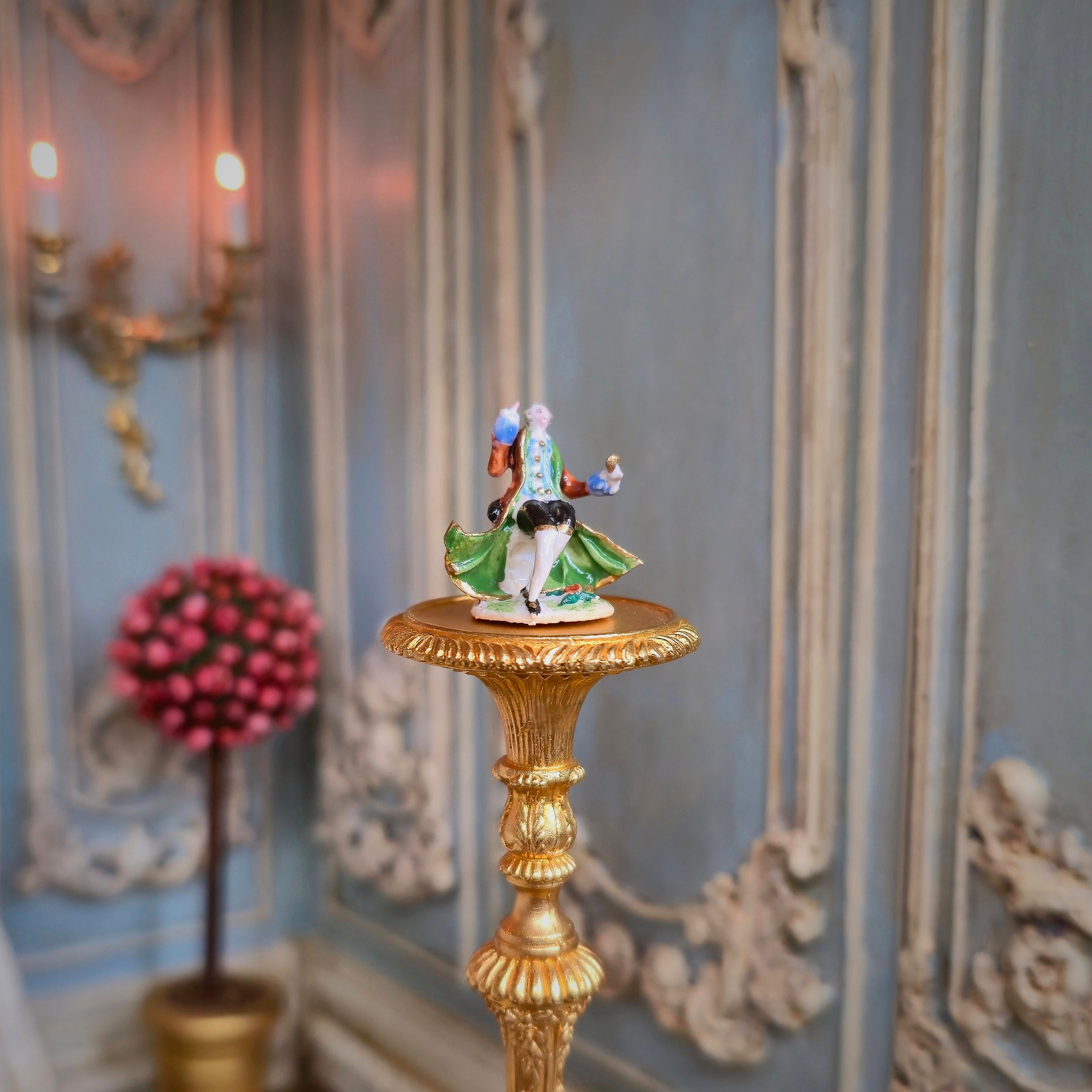 Decorative figurine on a gold pedestal against an ornate wall.