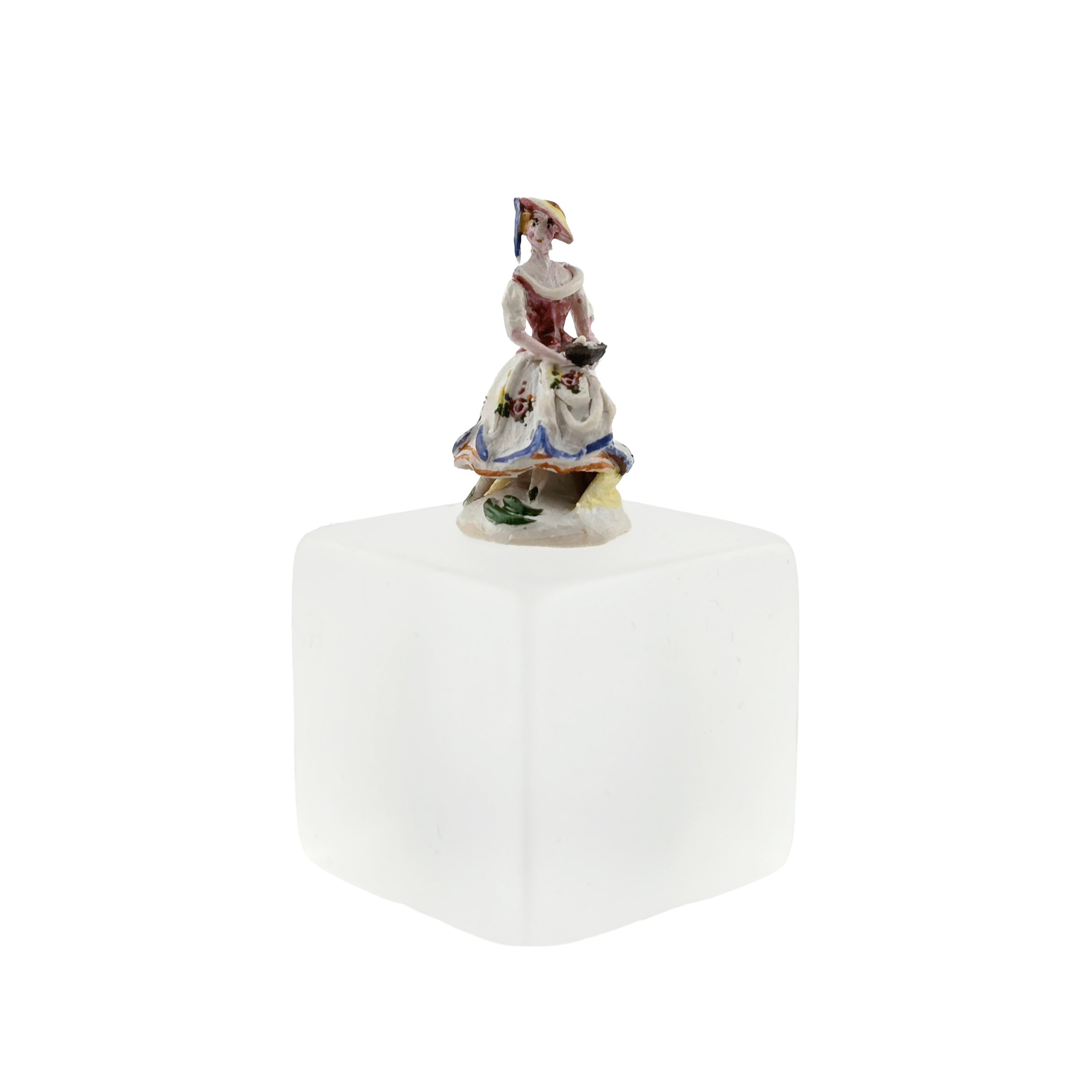 Decorative figurine on a white cube with a white background