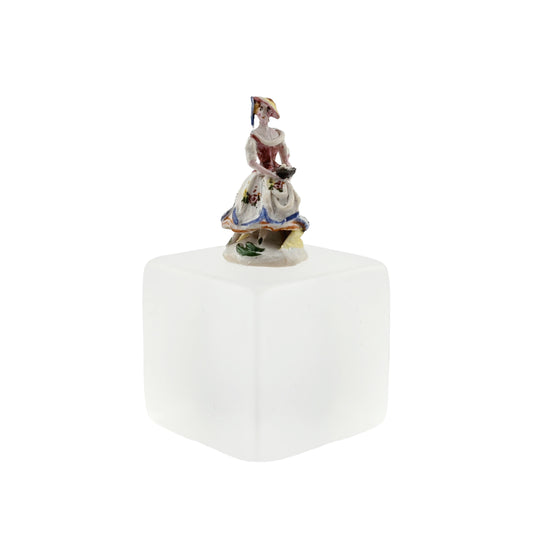 Decorative figurine on a white cube with a white background