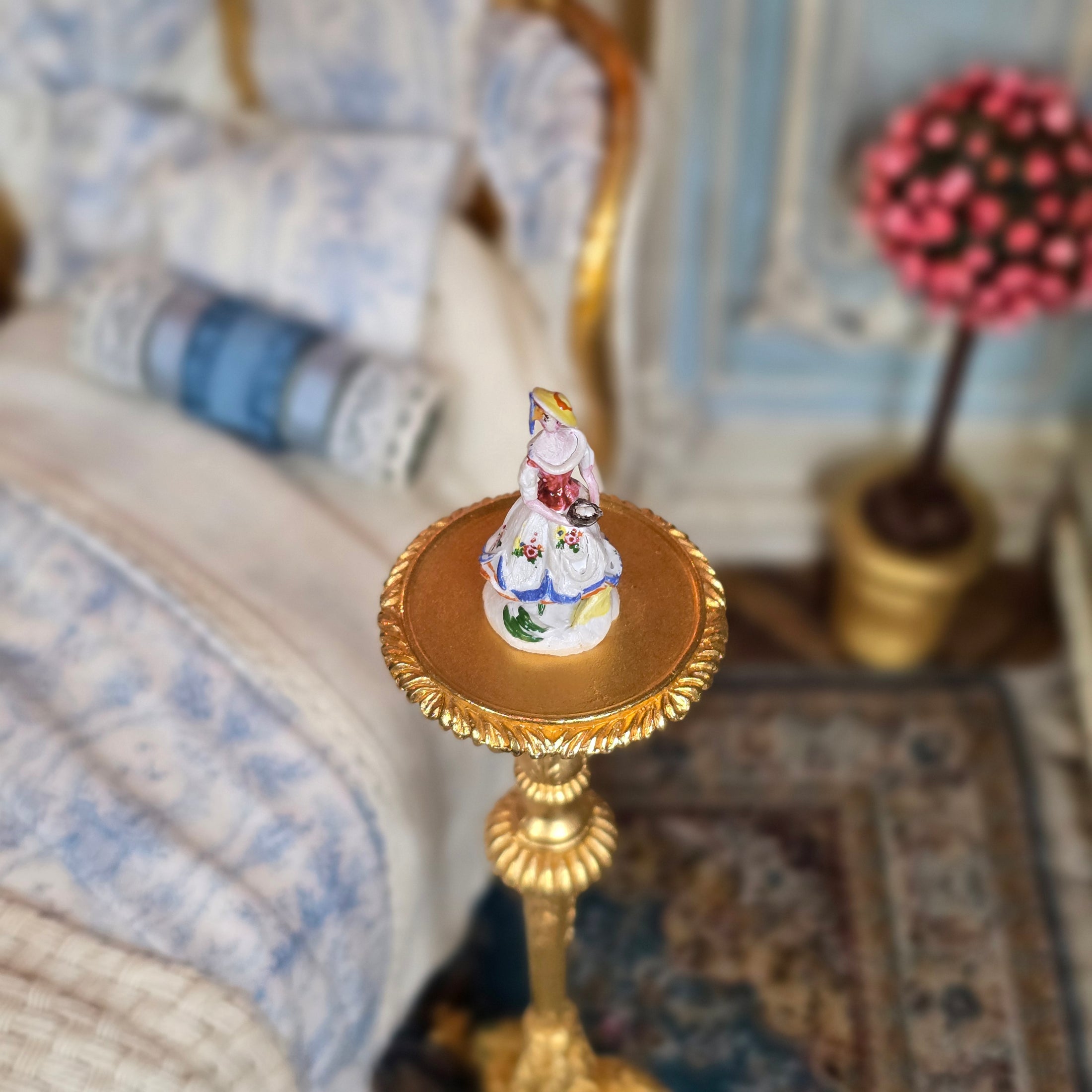 Decorative element with a small figurine on a gold base against a blurred background