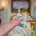 Load image into Gallery viewer, Decorative figurine held on a finger with a blurred ornate background
