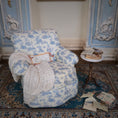 Load image into Gallery viewer, Patterned armchair in a room with decorative elements and scattered papers.
