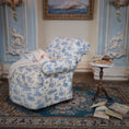 Load image into Gallery viewer, Decorative armchair with blue floral pattern in a room with ornate decor and books on a table.
