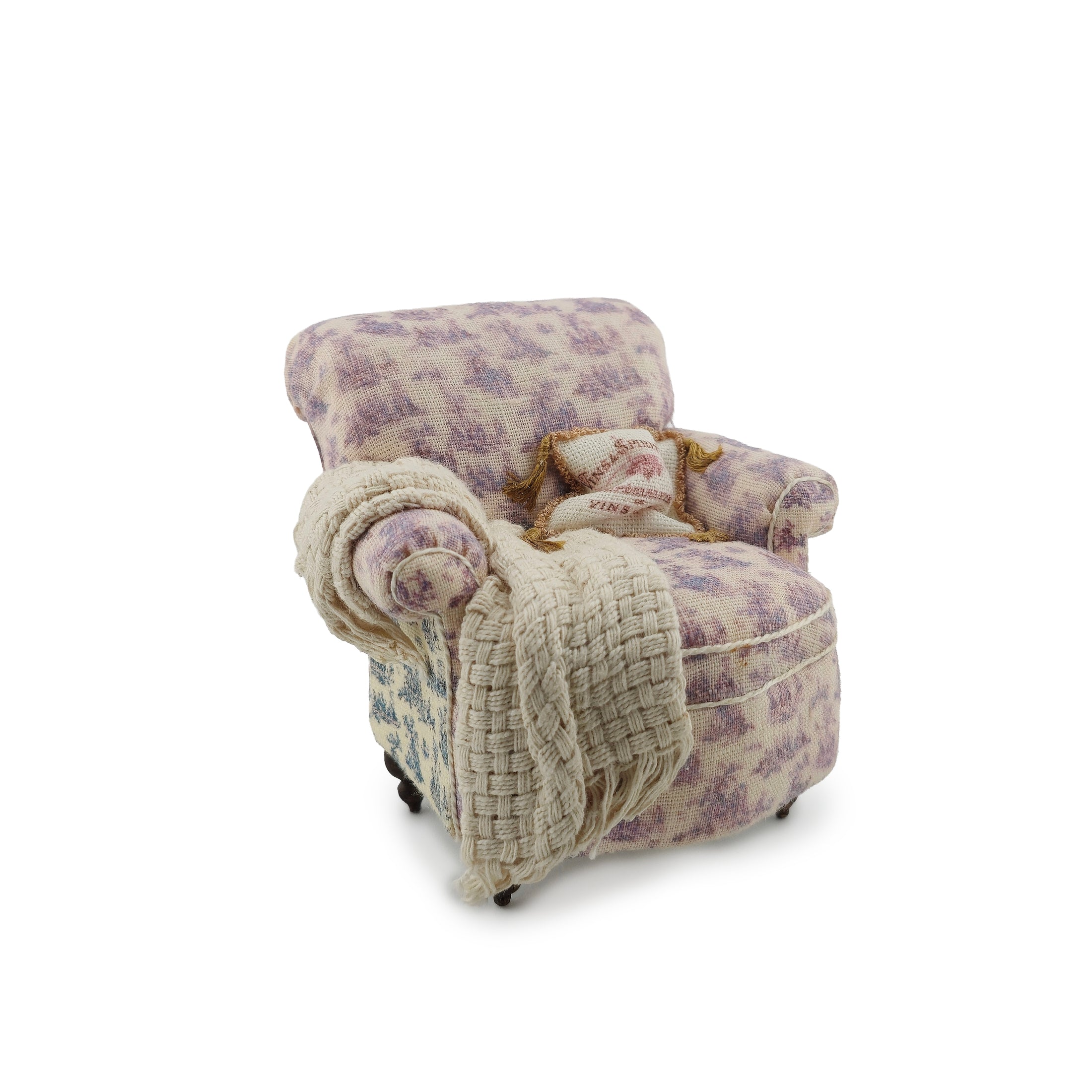 Floral patterned armchair with a beige blanket on a white background