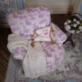 Load image into Gallery viewer, Decorative pillow with floral pattern and text on an upholstered armchair.
