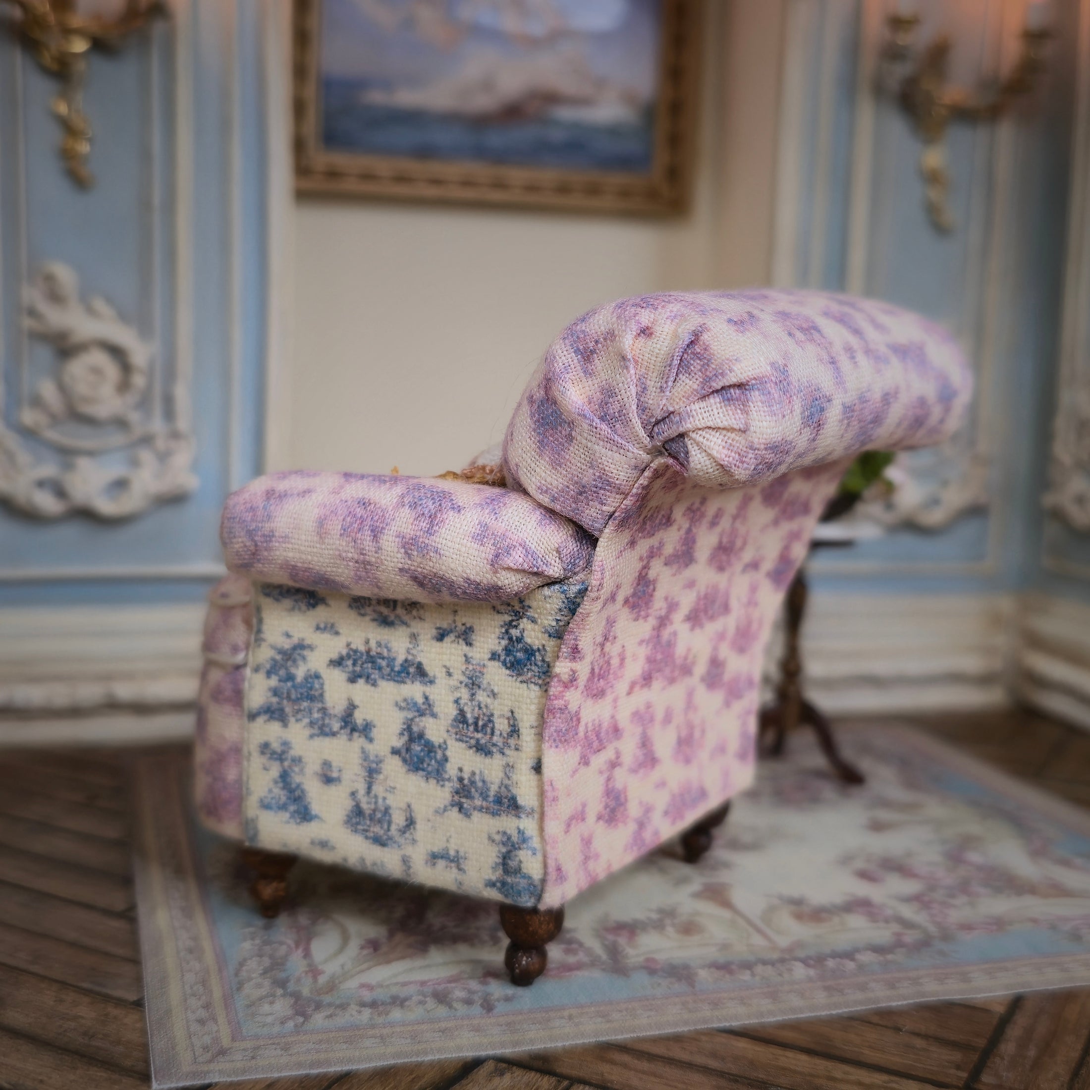 Floral-patterned armchair in a decorative room with a painting on the wall.