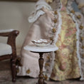 Load image into Gallery viewer, Small table with a decorative bowl in front of a doll wearing a floral dress.
