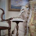 Load image into Gallery viewer, Vintage-style room with a small table holding a decorative bowl, armchair, and framed painting.
