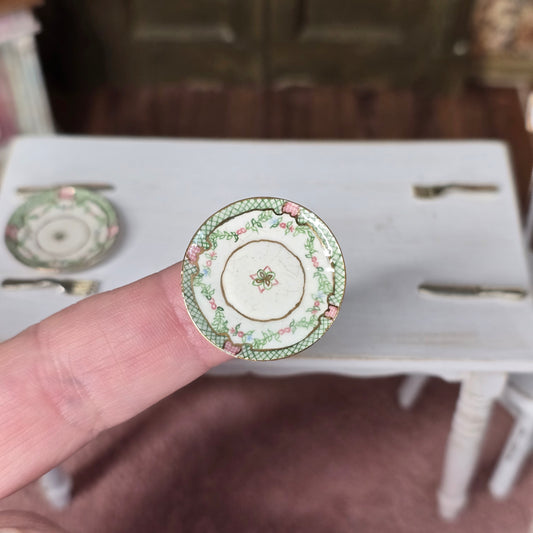 Small decorative plate held between fingers with a blurred background